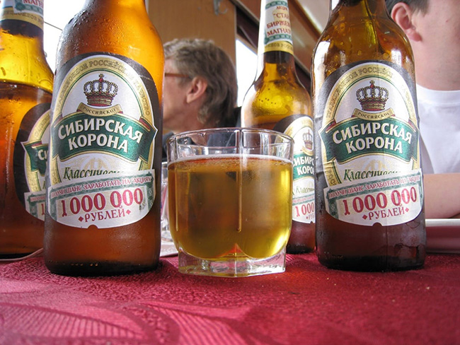 A table filled with cold beer bottles and one filled glass