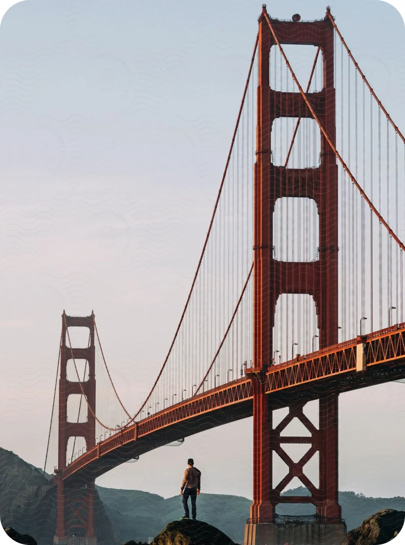 A hiker standing on a rock in front of the Golden Gate Bridge