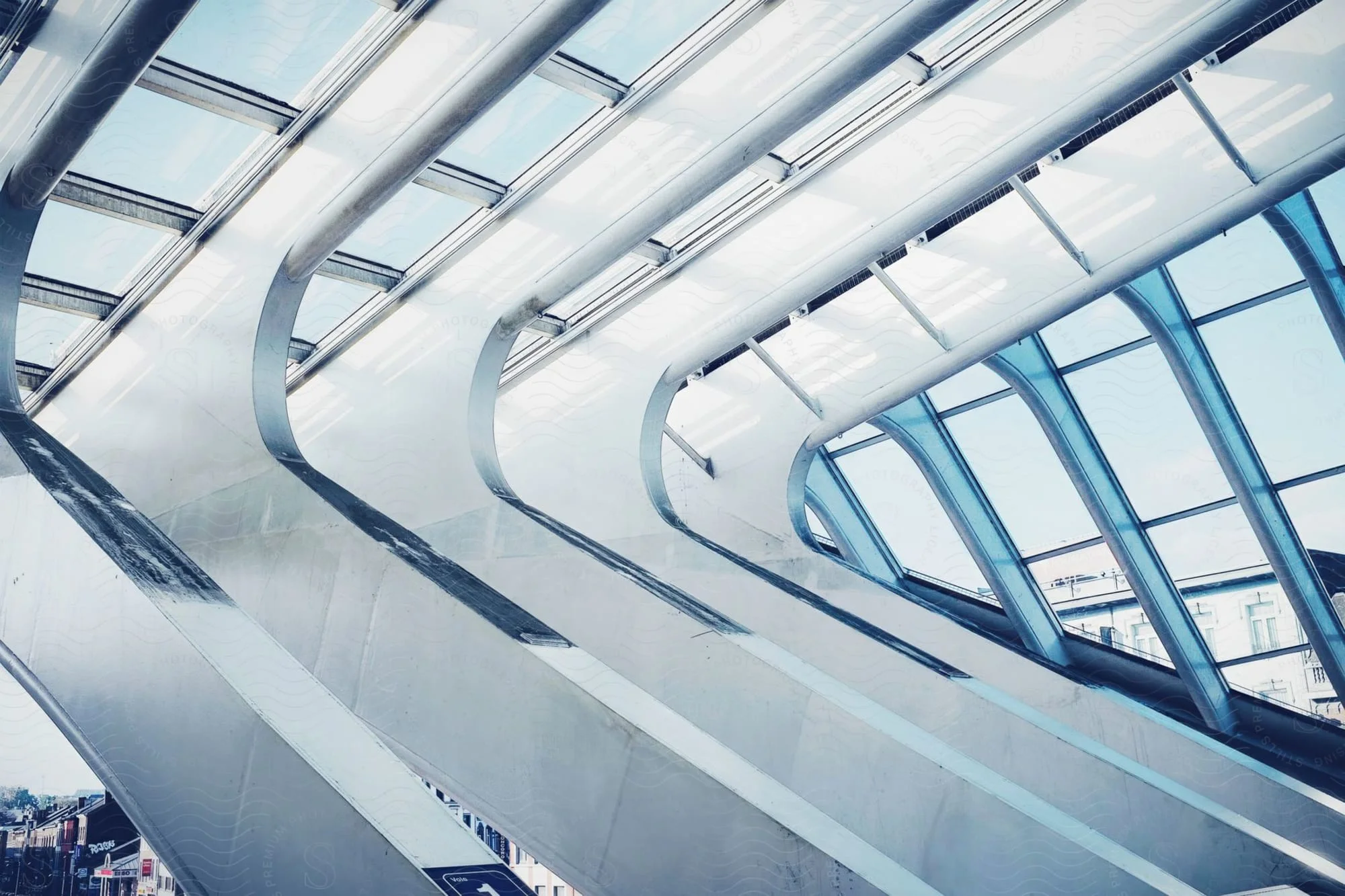 Looking up at the curved glass-and-steel roof of a transit hall