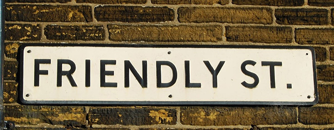 A street sign that reads, “Friendly St.” hung on a brick wall.
