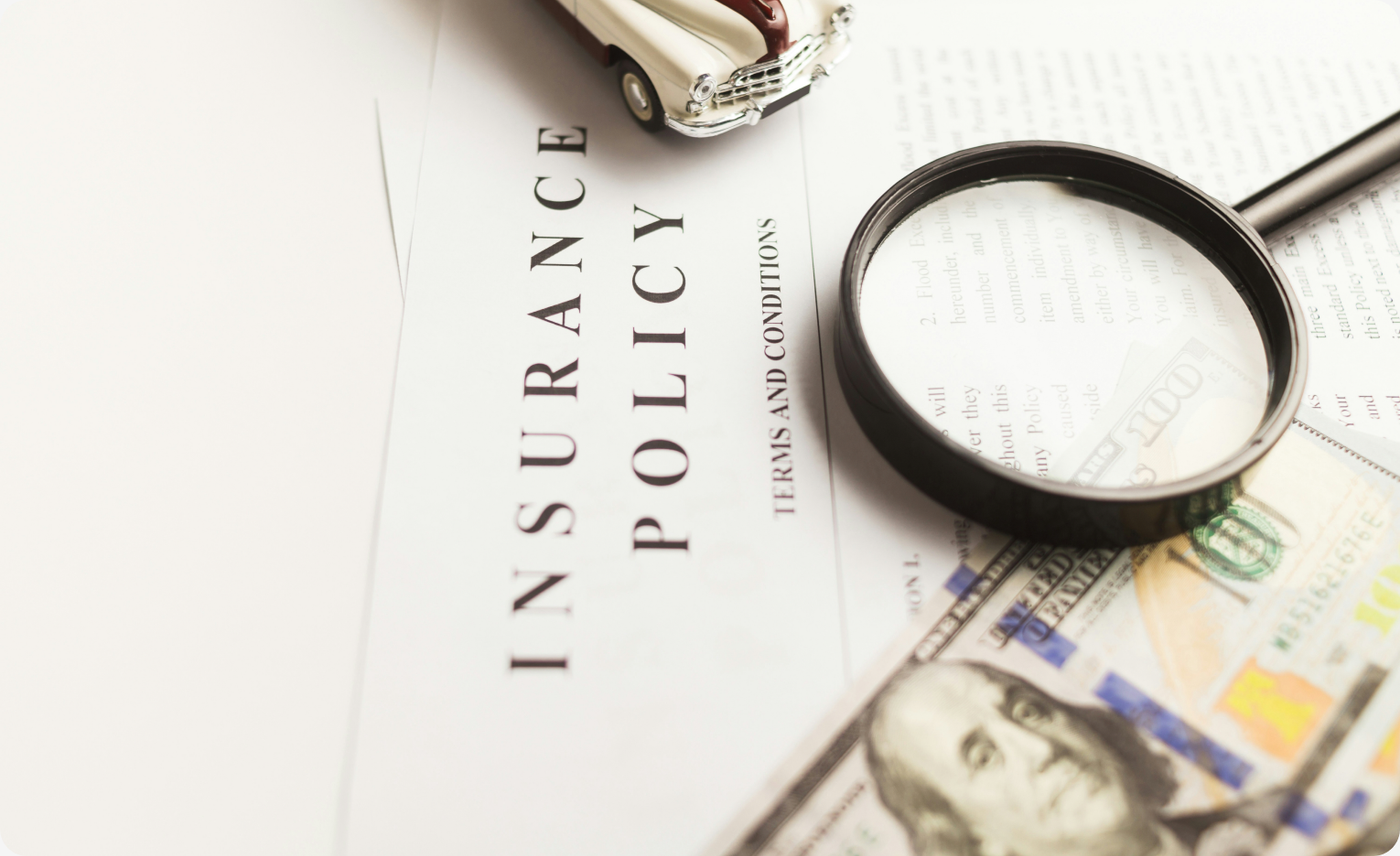 An insurance policy document with a magnifying glass and cash, representing claims and insurance fraud detection