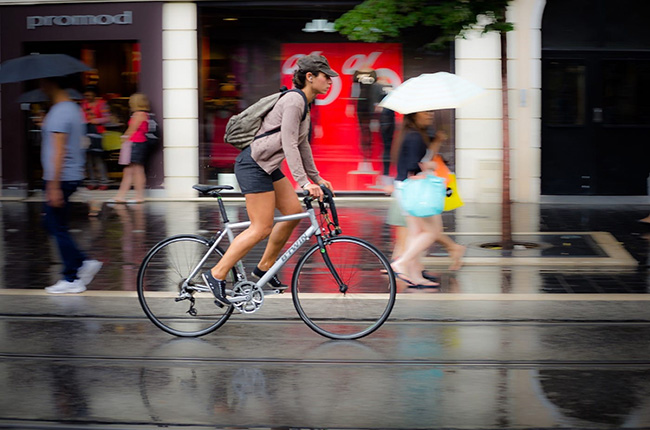 Courtesy of Kurt Bauschardt Woman riding a bicycle in the rain.
